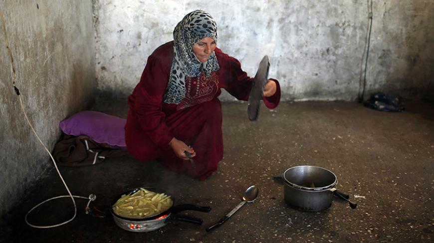 A Palestinian woman cooks at her house in the northern Gaza Strip May 26, 2014. REUTERS/Mohammed Salem (GAZA - Tags: SOCIETY) - RTR3QYQN