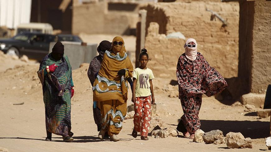 Indigenous Sahrawi women walk through Al Smara desert refugee camp in Tindouf, southern Algeria March 4, 2016. In refugee camps near the town of Tindouf in arid southern Algeria, conditions are hard for indigenous Sahrawi residents. Residents use car batteries for electricity at night and depend on humanitarian aid to get by. The five camps near Tindouf are home to an estimated 165,000 Sahrawi refugees from the disputed region of Western Sahara, according to the United Nations refugee agency UNHCR. REUTERS/
