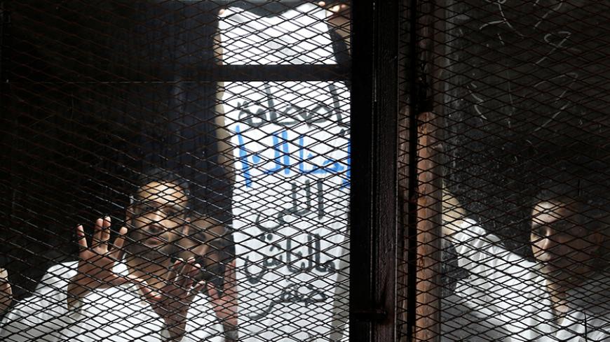 Egyptian journalists gesture behind bars during their trial at a court on the outskirts of Cairo, Egypt May 31, 2016. The banner reads, "Hey Press Syndicate, why is there no support for 10 of us?"  REUTERS/Amr Abdallah Dalsh - RTSFZK8