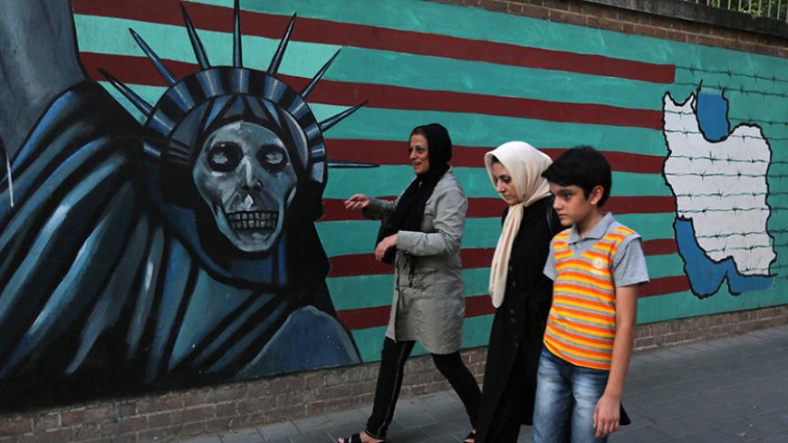 An Iranian family walks past anti-US graffiti on the wall of the former US embassy in Tehran on July 14, 2015. President Hassan Rouhani told Iranians that "all our objectives" have been met by a nuclear deal agreed Tuesday after epic talks with world powers. Slogan in Farsi reads, "Death to America". AFP PHOTO / ATTA KENARE        (Photo credit should read ATTA KENARE/AFP/Getty Images)