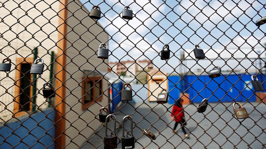 A woman walks behind a fence with padlocks left by prisoners, during a protest against the arrest of three prominent activists for press freedom, in front of Metris prison in Istanbul, Turkey, June 24, 2016. REUTERS/Murad Sezer - RTX2HYL8