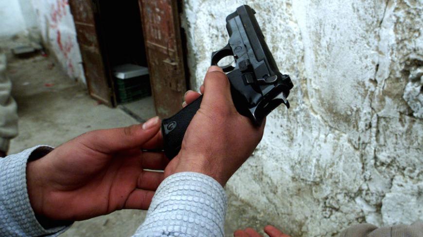 Palestinian teenagers handle a nine millimeter semi-automatic pistol in the Dheisheh refugee camp in Bethlehem January 4, 2001. The Dheisheh refugee camp hosts thousands of Palestinian refugees since the 1948 Israeli occupation. [Palestinian leader Yasser Arafat began consulting Arab leaders in Cairo on Thursday on U.S. President Bill Clinton's peace proposals before announcing whether he accepts them.   ] - RTXK7RJ
