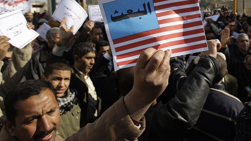 A protester holds up a poster symbolizing the U.S. flag which reads the word of "Baath" during a rally against the former Baath Party return in Baghdad, February 7, 2010. Iraq's Shi'ite parties held emotional demonstrations on Sunday and vowed to purge loyalists of Saddam Hussein's outlawed Baath party as tensions over a list of candidates banned from a March election soared.     REUTERS/Saad Shalash (IRAQ - Tags: CIVIL UNREST POLITICS) - RTR29X72