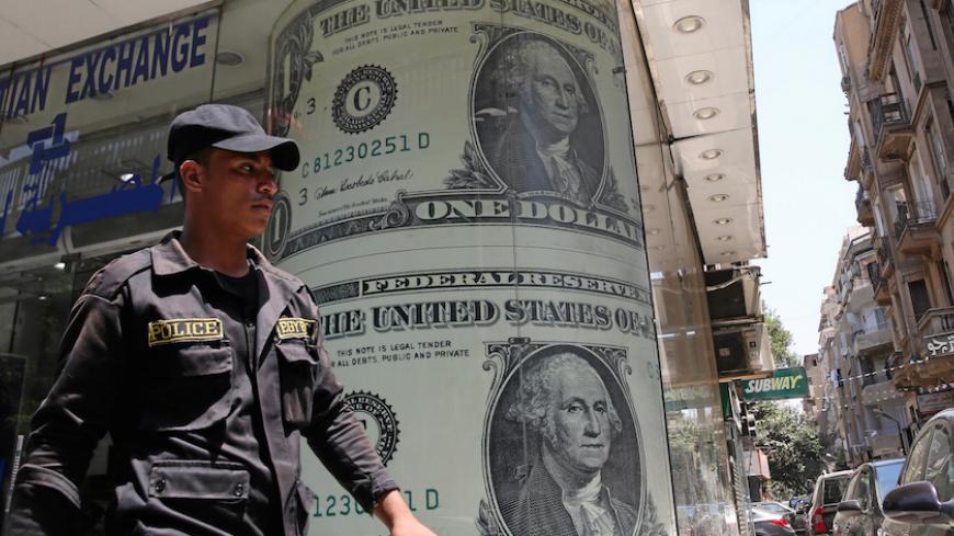 A policeman walks past a currency exchange bureau advertisement showing images of the U.S dollar and other currencies in Cairo, Egypt August 3, 2016. Picture taken August 3, 2016.   REUTERS/Mohamed Abd El Ghany - RTSMD9F