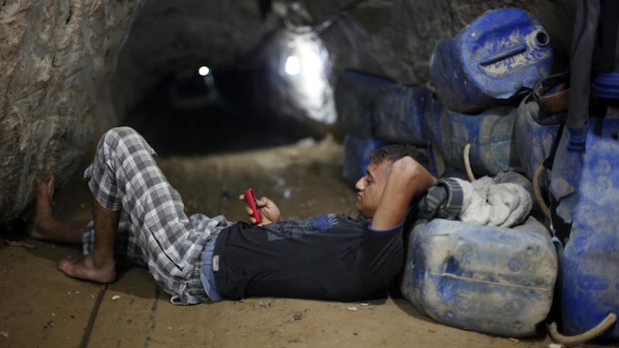 A Palestinian tunnel worker uses his mobile as he rests inside a smuggling tunnel beneath the Gaza-Egypt border in the southern Gaza Strip July 19, 2013. The Islamist group Hamas appealed to Egypt's new rulers on Thursday not to pursue its destruction of smuggling tunnels into the Gaza Strip, warning they risked throttling the small Palestinian territory. REUTERS/Ibraheem Abu Mustafa (GAZA - Tags: POLITICS TPX IMAGES OF THE DAY) - RTX11ROK