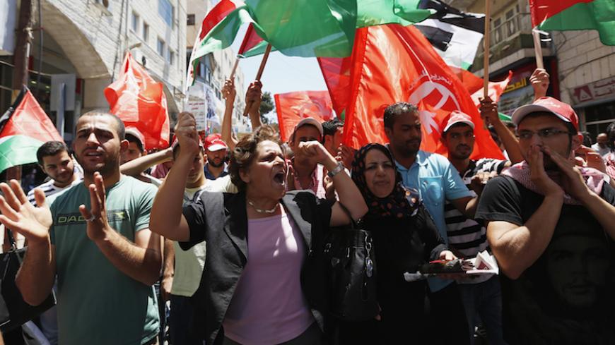 Palestinians wave Palestinian and Popular Front for the Liberation of Palestine (PFLP) flags during a protest against the renewal stalled peace talks with Israel,  in the West Bank city of Ramallah July 28, 2013. Israel was expected on Sunday to approve releasing more than 100 Arab prisoners as a step to renew stalled peace talks with the Palestinians ahead of plans to convene negotiators in Washington later this week. REUTERS/Mohamad Torokman (WEST BANK - Tags: POLITICS CIVIL UNREST) - RTX122EJ
