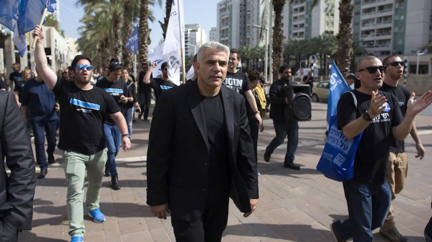 Yesh Atid leader Yair Lapid (C) walks with supporters as he campaigns in the southern city of Ashdod March 15, 2015. The era of Prime Minister Benjamin Netanyahu is ending, with Israeli voters clearly more concerned about economic and social issues than about security or fears over Iran, Lapid said on Monday. Lapid, a telegenic former news anchor and TV host, leads the centrist, secular Yesh Atid party ("There's a Future"), which emerged out of the cost-of-living protests that swept Israel in 2011. Picture 