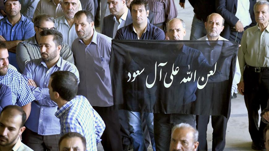 A man holds a banner that reads "God's curse on Al Saud (Saudi royal family)" during the funeral of victims killed in Saudi Arabia in a stampede at the haj pilgrimage, in Tehran October 4, 2015. More than 464 Iranian nationals were killed in last month's crush in Mina, Saudi Arabia, Iran's Haj Organization says. Iranian officials have alleged the overall total death toll is more than 1,000. Saudi Arabia has confirmed the deaths of 769 people. REUTERS/Raheb Homavandi/TIMAATTENTION EDITORS - THIS PICTURE WAS 