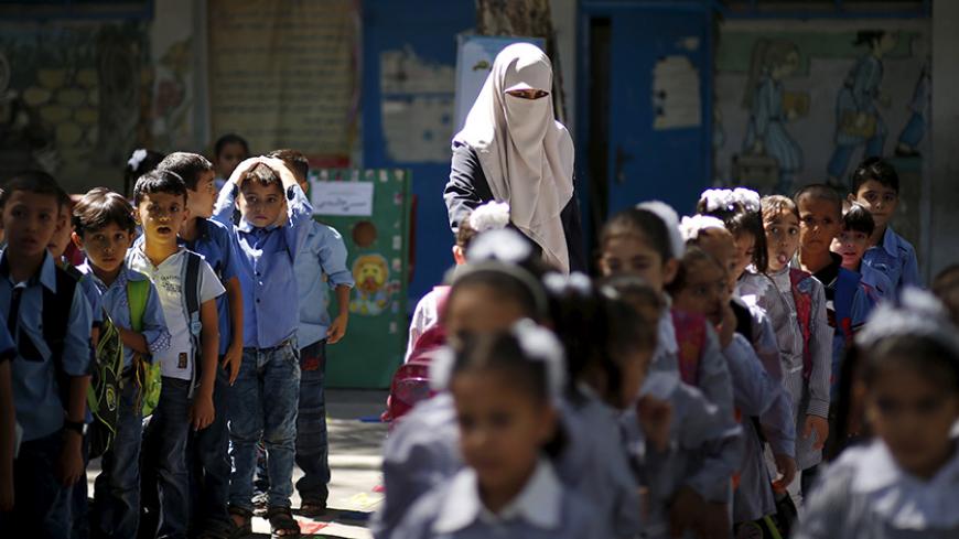 A veiled Palestinian teacher stands next to children as they queue at a United Nations Relief and Work Agency (UNRWA)-run school in Gaza September 22, 2015. As the United Nations celebrates its 70-year anniversary this year, Reuters documents the work of the organisation's main aid agency in the Gaza Strip, the United Nations Relief and Works Agency (UNRWA). The agency runs schools including the al-Nour (Light) School for the Blind and Visually Impaired Children in Gaza City and has helped families to repai