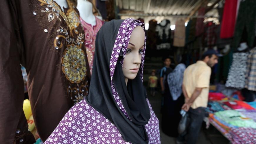 Palestinians shop as a mannequin displaying a headscarf and robe is seen at a market ahead of the Eid al-Adha festival in Khan Younis in the southern Gaza Strip September 23, 2015. Muslims across the world are preparing to celebrate the annual festival of Eid al-Adha or the Feast of the Sacrifice, which marks the end of the annual haj pilgrimage, by slaughtering goats, sheep, cows and camels in commemoration of the Prophet Abraham's readiness to sacrifice his son to show obedience to Allah. REUTERS/Ibraheem