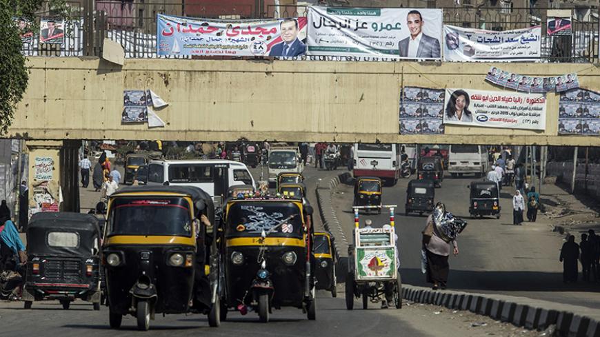 Egyptian drive rickshaws also known as "Tuk-tuks" along a road bearing portraits of candidates for the upcoming parliamentary elections in the Imbaba district of the Egyptian capital, Cairo, on October 15, 2015. Egyptians begin voting on the weekend for a parliament expected to step firmly in line behind President Abdel Fattah al-Sisi, who has crushed all opposition since ousting his Islamist predecessor in 2013. AFP PHOTO / KHALED DESOUKI        (Photo credit should read KHALED DESOUKI/AFP/Getty Images)
