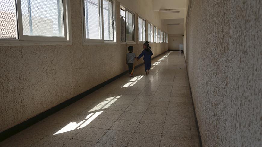 Displaced children walk in a hallway at a school where their family has been taking refuge since clashes started between members of the Libyan pro-government forces, backed by the locals, and Shura Council of Libyan Revolutionaries, an alliance of former anti-Gaddafi rebels who have joined Islamist group Ansar al-Sharia, in Benghazi, Libya April 30, 2015. After a year of war, Libya's second-largest city Benghazi is divided into areas controlled by forces loyal to one of two rival Libyan governments, and are