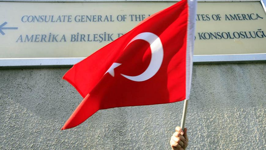 A protester holds a Turkish flag under a sign of the U.S. consulate in Istanbul, during a demonstration against the U.S. policy over northern Iraq as well as the killing of Turkish soldiers by PKK Kurdish rebels in southeast Turkey, October 26, 2007. Turkish helicopters ferried more troops to the border with Iraq on Friday as diplomatic efforts got under way in Ankara to avert a major offensive against Kurdish guerrillas based in northern Iraq.    REUTERS/Fatih Saribas  (TURKEY) - RTR1VCO0