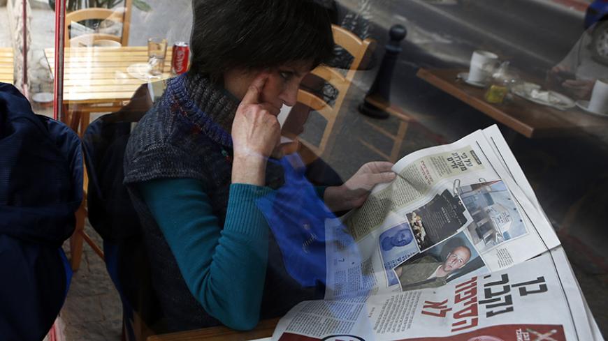 A woman is seen through a coffee shop window as she reads an article about Ben Zygier in an Yedioth Ahronoth newspaper in Jerusalem February 15, 2013. Zygier, the Australian immigrant reported to have been recruited by Israel's Mossad spy agency, was charged with grave crimes before he committed suicide in an Israeli jail, one of his lawyers said on Thursday. REUTERS/Baz Ratner (JERUSALEM - Tags: POLITICS CRIME LAW) - RTR3DTPG