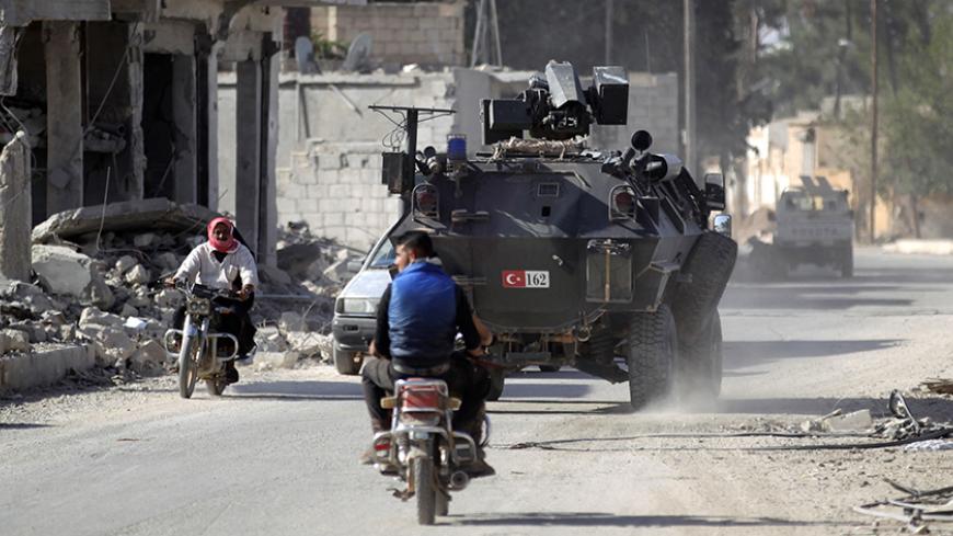 Men ride motorbikes past a Turkish armored carrier in the northern Syrian rebel-held town of al-Rai, in Aleppo Governorate, Syria, October 5, 2016. REUTERS/Khalil Ashawi - RTSQWHY