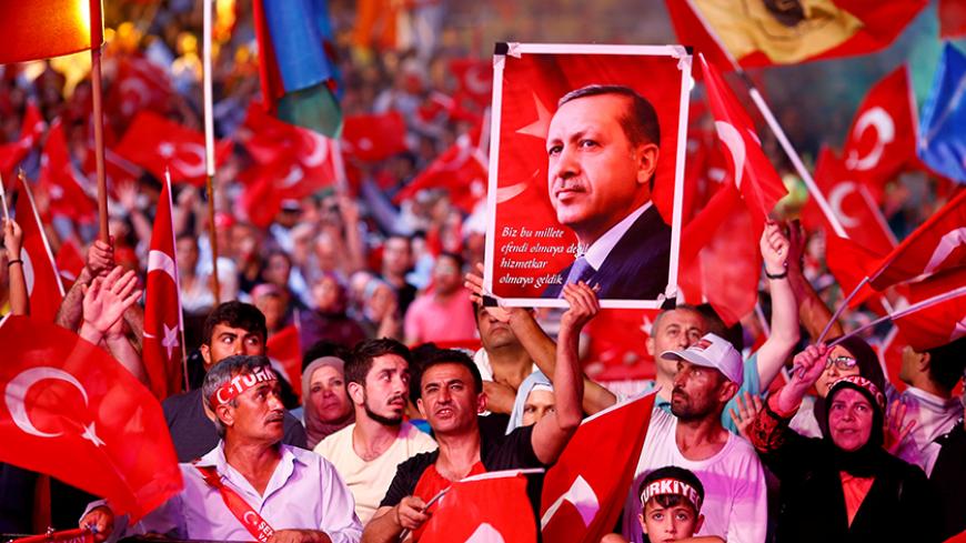 Supporters of Turkish President Recep Tayyip Erdogan wave national flags as they listen to him through a giant screen in Istanbul's Taksim Square, Turkey, August 10, 2016. REUTERS/Osman Orsal/File Photo - RTSRR8G