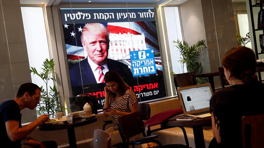 People dine at a coffee shop as an image of newly elected U.S. President Donald Trump is displayed on a monitor in Tel Aviv, Israel November 9, 2016. REUTERS/Baz Ratner - RTX2SSC5