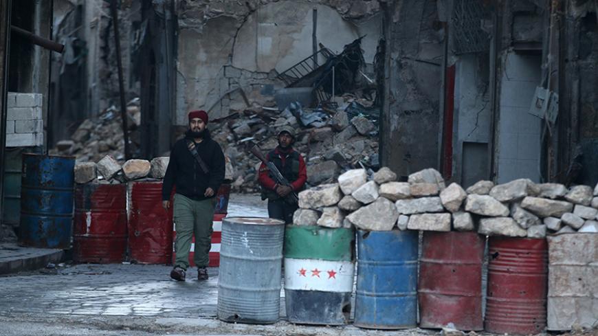 A rebel fighter stands with his weapon near damaged buildings, and barricades with a Free Syrian Army flag drawn(C), in rebel-held besieged old Aleppo, Syria December 2, 2016. REUTERS/Abdalrhman Ismail - RTSUDX4
