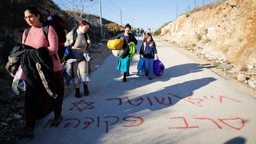 Israeli teenagers walk on graffiti reading in Hebrew "Soldier, policeman, refuse orders" as they prepare for an expected eviction of the Jewish settlement outpost of Amona in the West Bank, December 9, 2016. REUTERS/Amir Cohen     TPX IMAGES OF THE DAY - RTSVF4Q