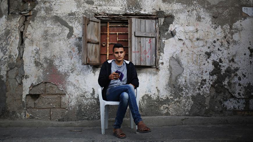 A Palestinian man plays with his mobile the Shati refugee camp in Gaza City on April 13, 2014. AFP PHOTO/MOHAMMED ABED        (Photo credit should read MOHAMMED ABED/AFP/Getty Images)