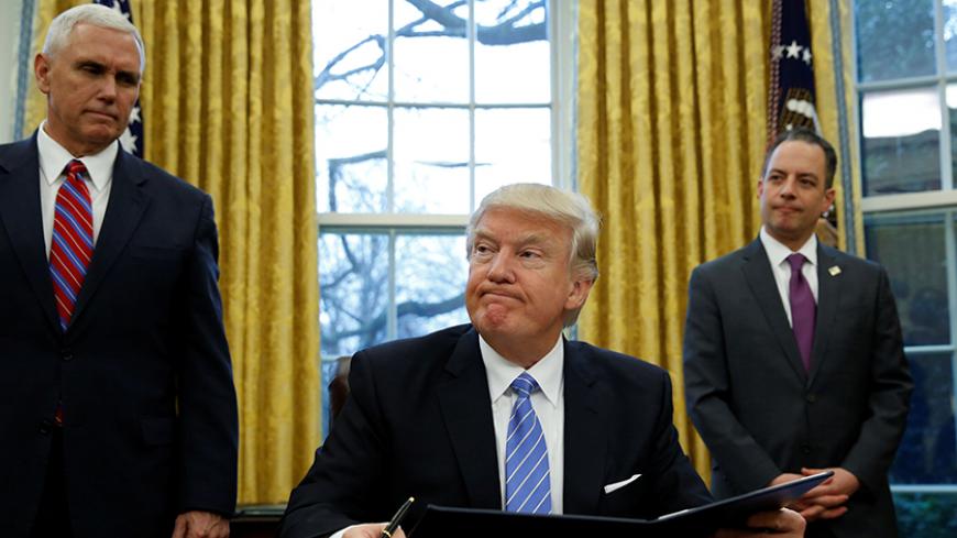 U.S. President Donald Trump, flanked by Vice President Mike Pence (L) and White House Chief of Staff Reince Priebus (R), looks up while signing an executive order on the reinstatement of the Mexico City Policy in the Oval Office of the White House in Washington January 23, 2017.   REUTERS/Kevin Lamarque - RTSWZZR