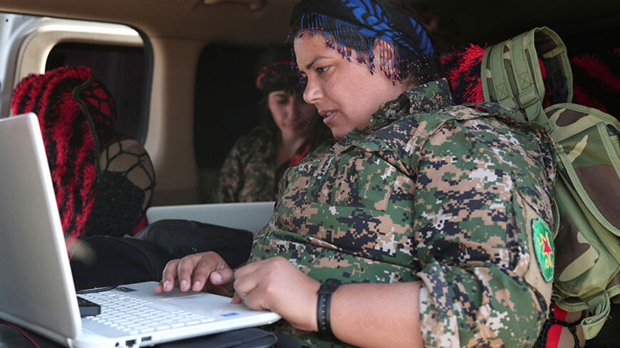 A Kurdish fighter from the People's Protection Units (YPG), operating alongside with the Syrian Democratic Forces (SDF), sits inside a vehicle as she works on a laptop in the town of Hisha after the SDF took control of the area from Islamic State militants, in the northern Raqqa countryside, Syria November 14, 2016. REUTERS/Rodi Said - RTX2TNGJ