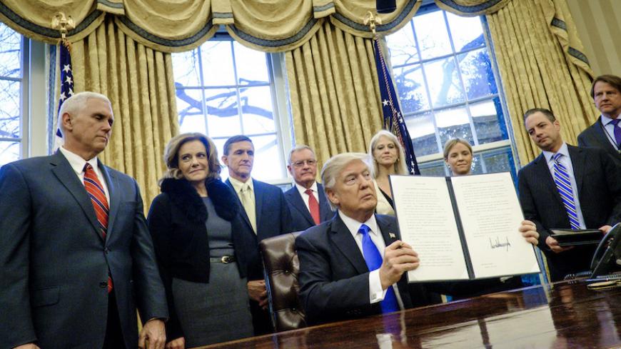 WASHINGTON, DC - JANUARY 28: President Donald Trump holds up one of the executive actions that he signed in the Oval Office on January 28, 2017 in Washington, DC. The actions outline a reorganization of the National Security Council, implement a five year lobbying ban on administration officials and a lifetime ban on administration officials lobbying for a foreign country and calls on military leaders to present a report to the president in 30 days that outlines a strategy for defeating ISIS.  (Photo by Pet