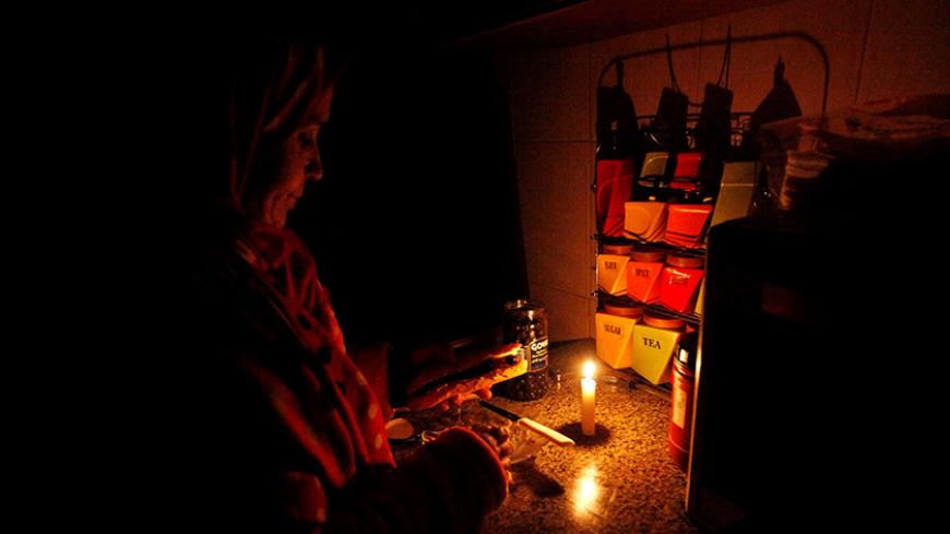 A woman prepares breakfast in candlelight during a blackout inside a kitchen in her house in Tripoli, Libya, January 15, 2017. REUTERS/Ismail Zitouny - RTSVKY8