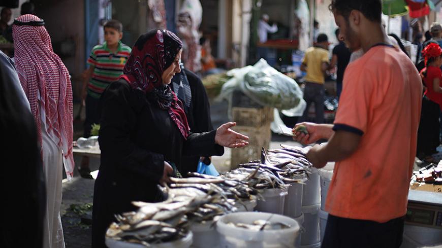 A Palestinian woman buys traditional fish eaten during Eid, ahead of the Muslim Eid al-Fitr holiday, at a market in Khan Younis in the southern Gaza Strip August 7, 2013. REUTERS/Ibraheem Abu Mustafa (GAZA - Tags: RELIGION ANNIVERSARY) - RTX12COG
