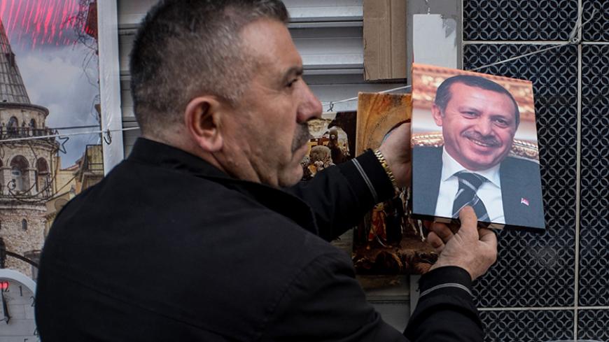 ISTANBUL, TURKEY - FEBRUARY 23: A man selling paintings packs up a print of Turkey's President Recep Tayyip Erdogan as he closes his stall for the day on February 23, 2017 in Istanbul, Turkey. Turkey will hold its constitutional referendum on April 16, 2017. Turks will vote on 18 proposed amendments to the Constitution of Turkey. The controversial changes seek to replace the parliamentary system and move to a presidential system which would give President Recep Tayyip Erdogan executive authority. Campaignin