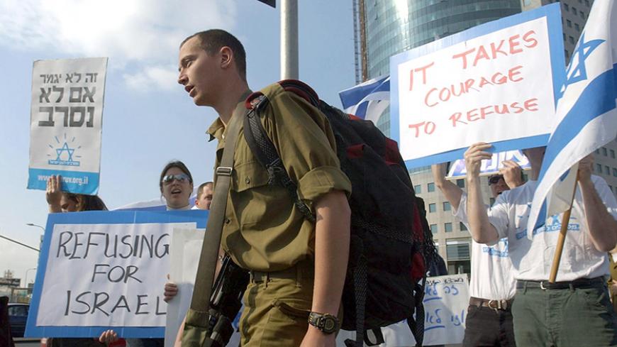 An Israeli soldier passes a demonstration by left-wing Israelis calling on army recruits to refuse to serve in the Palestinian territories, as they protest outside the Defense Ministry in Tel Aviv 18 March 2004. AFP PHOTO/Tal COHEN        (Photo credit should read TAL COHEN/AFP/Getty Images)