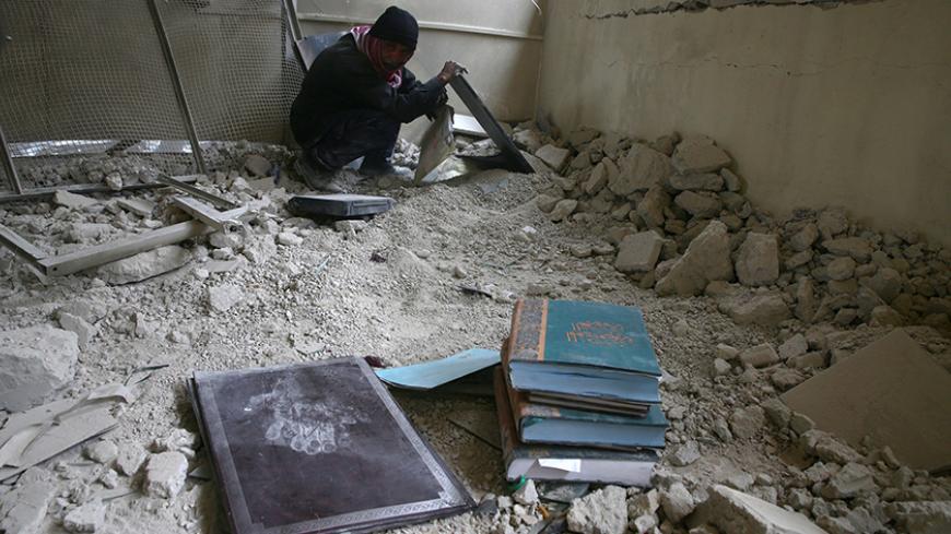 A man inspects books inside a damaged school in the rebel held besieged city of Douma, in the eastern Damascus suburb of Ghouta, Syria March 2, 2017. REUTERS/Bassam Khabieh - RTS117AV