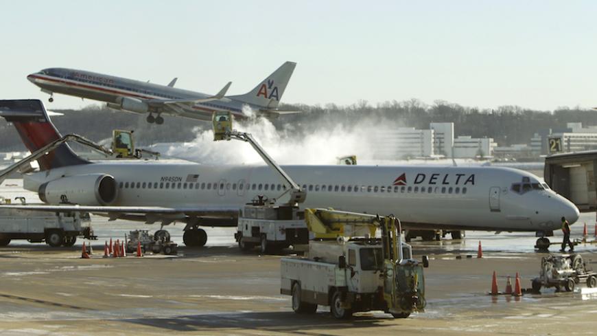 A Delta jetliner (foreground) is de-iced while an American Airlines plane (rear) takes off at Reagan National Airport in Washington January 3, 2014. A heavy snowstorm and dangerously cold conditions gripped the northeastern United States on Friday, delaying flights, paralyzing road travel and closing schools and government offices across the region.   REUTERS/Gary Cameron    (UNITED STATES - Tags: ENVIRONMENT TRANSPORT TRAVEL) - RTX1711Z