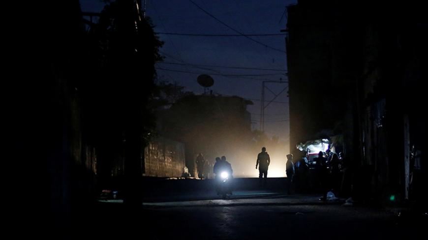 Palestinians ride a motorcycle during a power cut on a street in Beit Lahiya in the northern Gaza Strip January 11, 2017. Picture taken January 11, 2017. REUTERS/Mohammed Salem - RTX2YLZ2