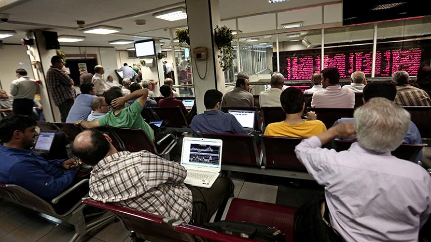 Iranians check economic diagrams on their laptops while monitoring a stock market activity board at the stock exchange in the capital Tehran on July 27, 2015. Iran's central bank chief said that Iran has assets of $29 billion in overseas banks that could be unlocked under a nuclear deal struck on July 14, far less than reported estimates of over $100 billion. AFP PHOTO / BEHROUZ MEHRI        (Photo credit should read BEHROUZ MEHRI/AFP/Getty Images)