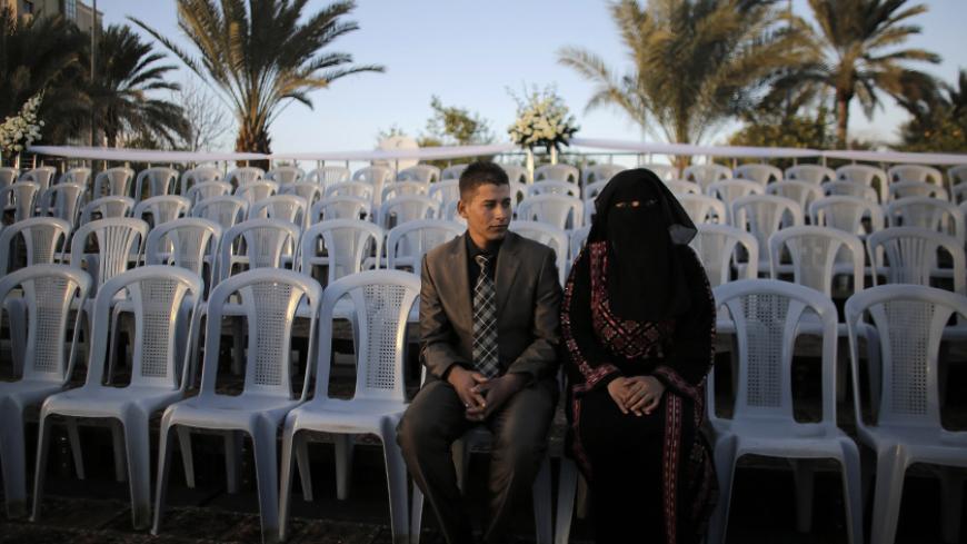 A Palestinian couple waits before a mass wedding ceremony in the West Bank city of Jericho January 28, 2014. A spokesman working together with the Palestinian Presidential Office said some 300 Palestinian couples, 80 of them from the Gaza Strip, wedded on Tuesday in the mass ceremony funded by the Presidential Office and attended by President Mahmoud Abbas. Each couple would also be given $4,000, the spokesman said.   REUTERS/Ammar Awad (WEST BANK - Tags: SOCIETY) - RTX17YR6