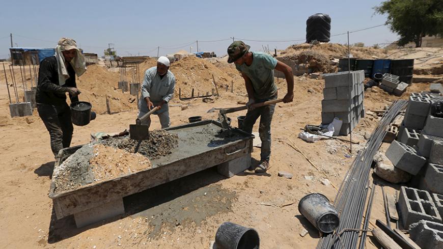 Palestinian labourers work at the construction site of a house, that witnesses said was destroyed by Israeli shelling during a 50-day war last summer, in Johr El-Deek village near the central Gaza Strip July 26, 2015.  The house is rebuilt as part of a Qatari-funded project aimed at reconstructing housing units destroyed during the war. Palestinian Minister of Housing and Public Works Mufeed Al-Hassayna said that the reconstruction process in Gaza has started, almost a year since the 2014 war. More than 100