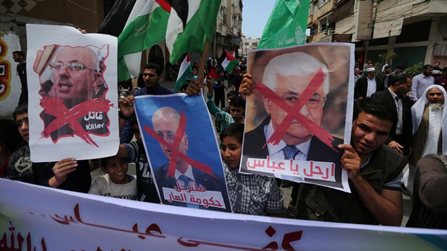 Hamas supporters hold crossed posters depicting Palestinian President Mahmoud Abbas and Palestinian Prime Minister Rami Hamdallah during a protest against them in Khan Younis in the southern Gaza Strip April 14, 2017. REUTERS/Ibraheem Abu Mustafa - RTX35JYQ