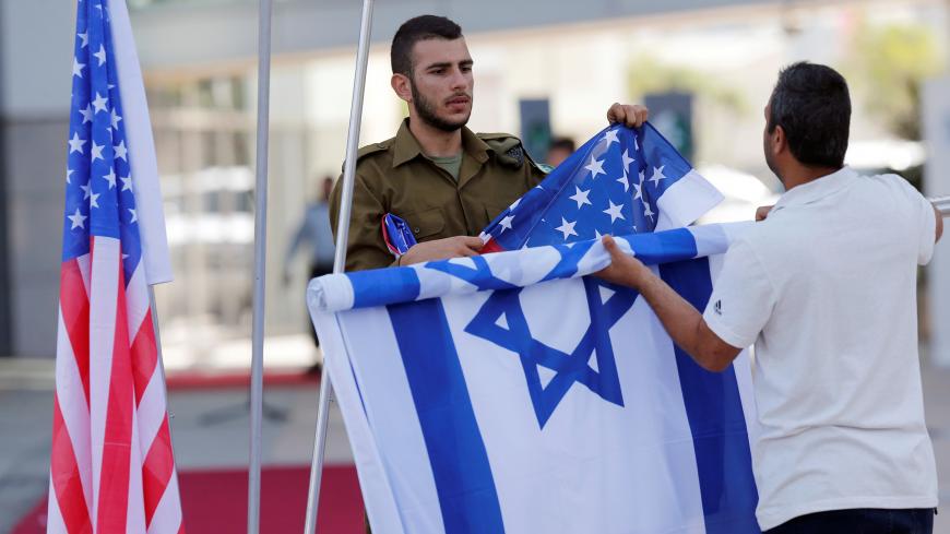 An Israeli soldier (L) helps to roll up the Israeli and American flags after an honor guard ceremony held for General Joseph Dunford, the Chairman of the U.S. Joint Chiefs of Staff, in Tel Aviv, Israel May 9, 2017. REUTERS/Nir Elias - RC157C6035A0