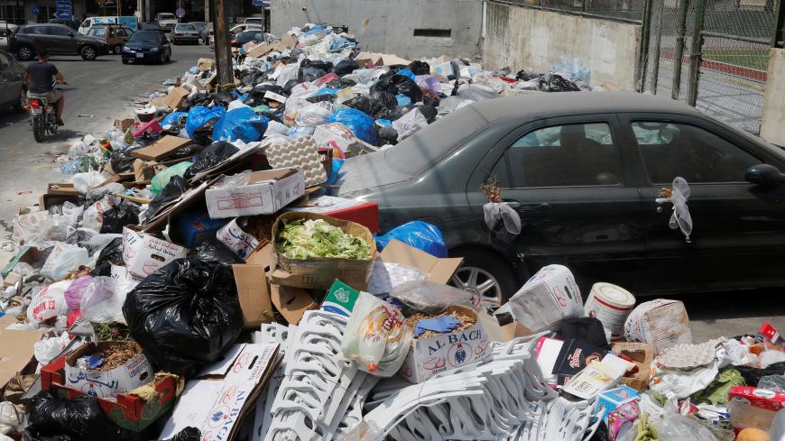 A car is blocked by garbage piled up along a street in Dekwaneh area, Mount Lebanon August 29, 2016. REUTERS/Mohamed Azakir  - S1AETYGHNHAA