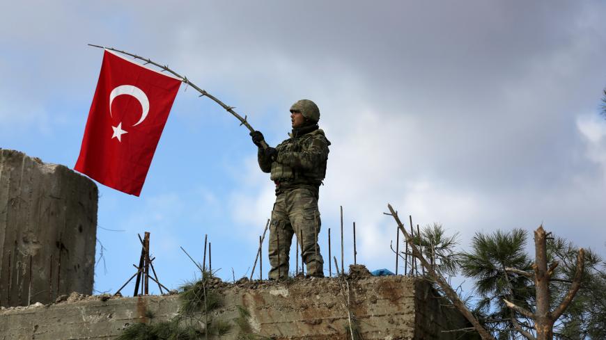 A Turkish soldier waves a flag on Mount Barsaya, northeast of Afrin, Syria January 28 ,2018. REUTERS/ Khalil Ashawi - RC13E270E570