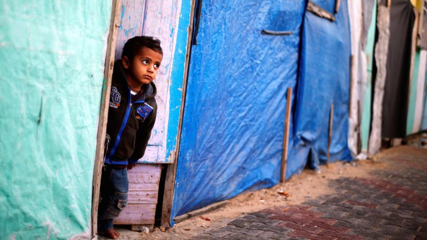 A Palestinian boy who lives in a container as a temporary replacement for his house that was destroyed in the 2014 war, looks out on a rainy day in Beit Hanoun in the northern Gaza Strip December 15, 2016.  REUTERS/Suhaib Salem - RC1DAD9F6BE0