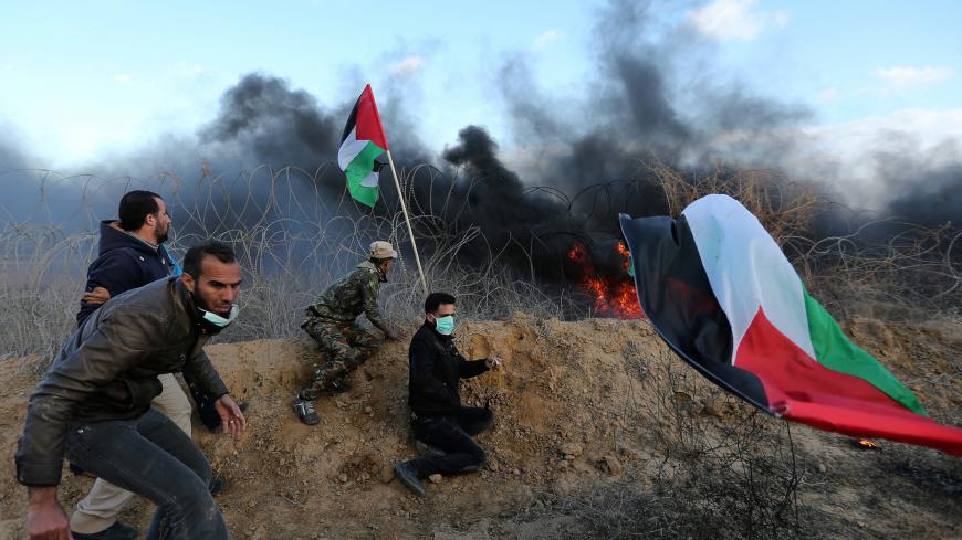 Palestinian demonstrators take cover during clashes with Israeli troops, as Palestinians call for 'a day of rage' against U.S. President Donald Trump's decision over Jerusalem, near the border with Israel in the southern Gaza Strip January 26, 2018. REUTERS/Ibraheem Abu Mustafa - RC1C425317D0