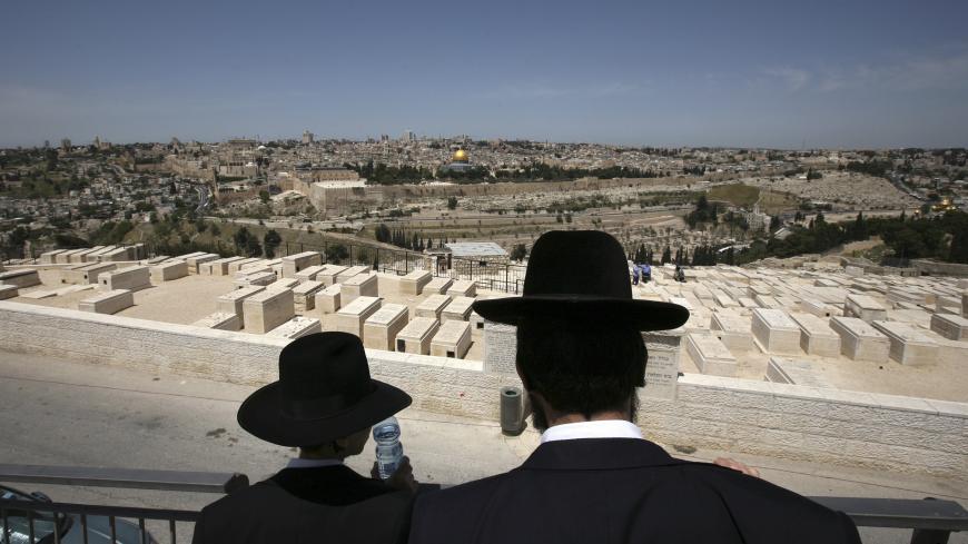 Ultra-Orthodox Jews visit the military cemetery on the Mount of Olives in Jerusalem April 28, 2009. Israel on Tuesday marks Memorial Day to commemorates its fallen soldiers. The Dome of the Rock on the compound known to Muslims as al-Haram al-Sharif, and to Jews as Temple Mount, is seen in the background. REUTERS/Yannis Behrakis (JERUSALEM ANNIVERSARY POLITICS MILITARY RELIGION) - GM1E54S1GYT01