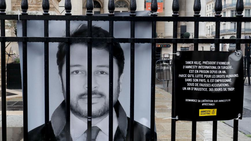 A portrait of rights group NGO Amnesty International's chairman in Turkey Taner Kilic is hung on June 6, 2018 on the fence of the historic French stock market building "Palais Brongniart" in Paris, to protest against Kilic's custody since a year for allegedly belonging to the movement led by an US-based Muslim preacher, whom Turkey accuses of ordering the 2016 coup bid. (Photo by FRANCOIS GUILLOT / AFP)        (Photo credit should read FRANCOIS GUILLOT/AFP/Getty Images)