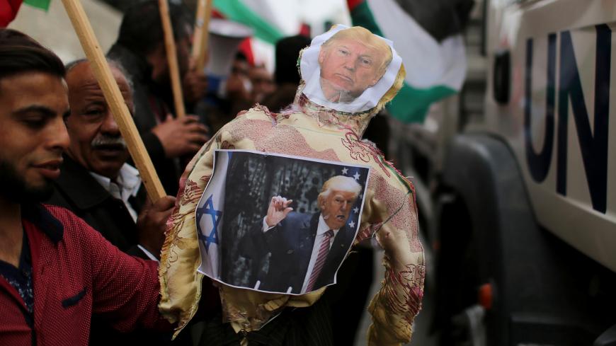 Palestinian demonstrators hold an effigy depicting U.S. President Donald Trump to be burnt during a protest against U.S aid cuts, outside the United Nations' offices in the southern Gaza Strip February 11, 2018. REUTERS/Ibraheem Abu Mustafa - RC19E00C32E0