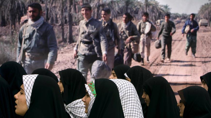 Women stand next to a picture of war veterans as they visit a war memorial site in Khoozestan province near the Iraqi border, 1,345 km (841 miles) southwest of Tehran, March 19, 2009. Iranians visit the main battlegrounds of the Iran-Iraq war (1980-88) during the last week of the Iranian calendar to remember martyrs who died in the war. REUTERS/Morteza Nikoubazl (IRAN ANNIVERSARY CONFLICT POLITICS) - GM1E53J1LIZ01