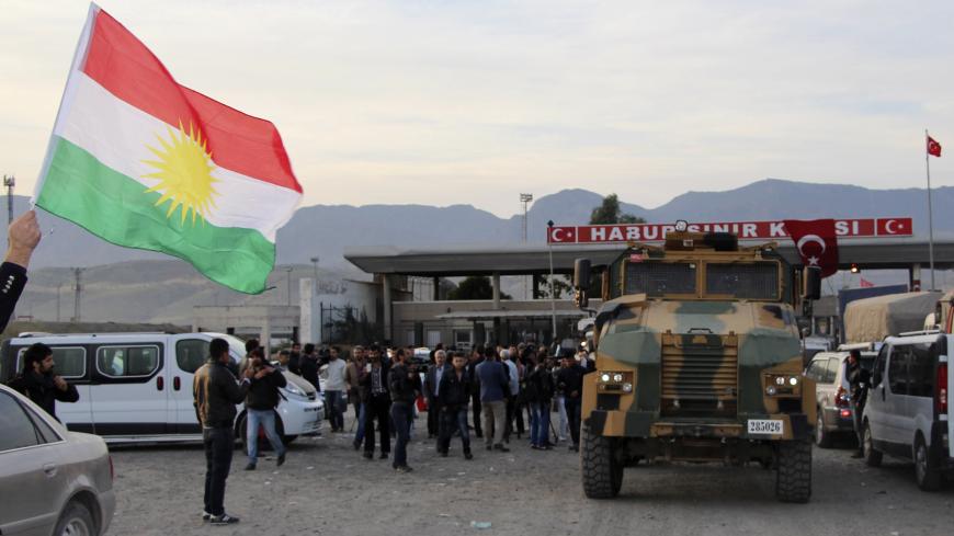 A man waves a Kurdistan flag as a Turkish military truck escorts a convoy of peshmerga vehicles at Habur border gate, which separates Turkey from Iraq, near the town of Silopi in southeastern Turkey, October 29, 2014. Iraqi peshmerga fighters arrived in southeastern Turkey early on Wednesday ahead of their planned deployment to the Syrian town of Kobani to help fellow Kurds repel an Islamic State advance, a Reuters witness said. REUTERS/Kadir Baris (TURKEY - Tags: POLITICS MILITARY CONFLICT TPX IMAGES OF TH