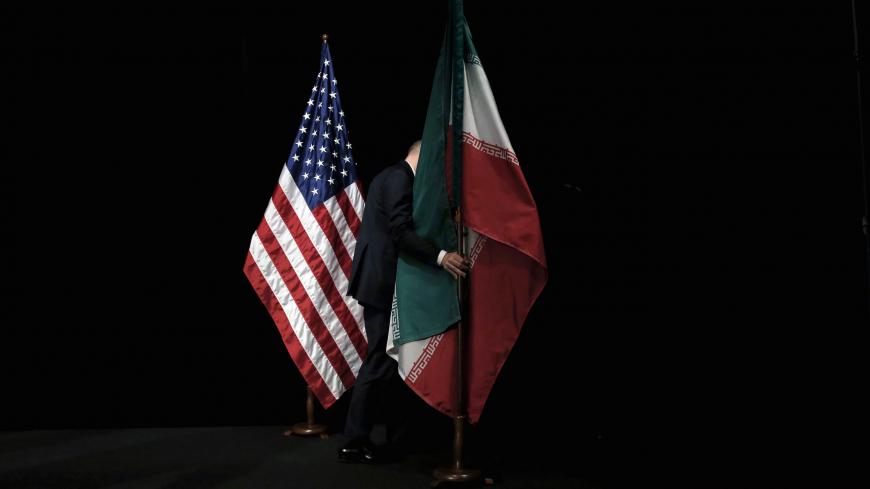 A staff member removes the Iranian flag from the stage after a group picture with foreign ministers and representatives of the U.S., Iran, China, Russia, Britain, Germany, France and the European Union during the Iran nuclear talks at the Vienna International Center in Vienna, Austria July 14, 2015. To match Analysis USA-ELECTION/IRAN      REUTERS/Carlos Barria/File Photo - S1AEULVWJEAA