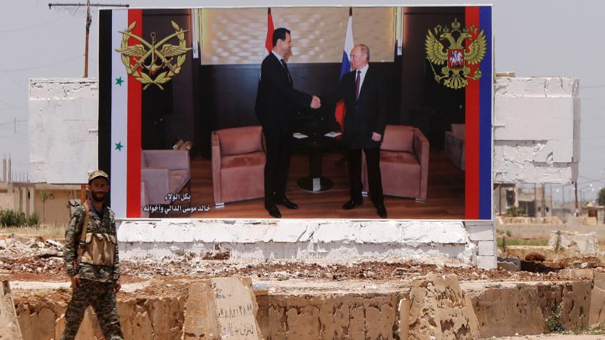 A soldier stands guard near a poster of Syria's President Bashar al Assad and his Russian counterpart Vladimir Putin during the re-opening of the road between Homs and Hama in Rastan, Syria,  June 6, 2018. REUTERS/Omar Sanadiki - RC153557C500